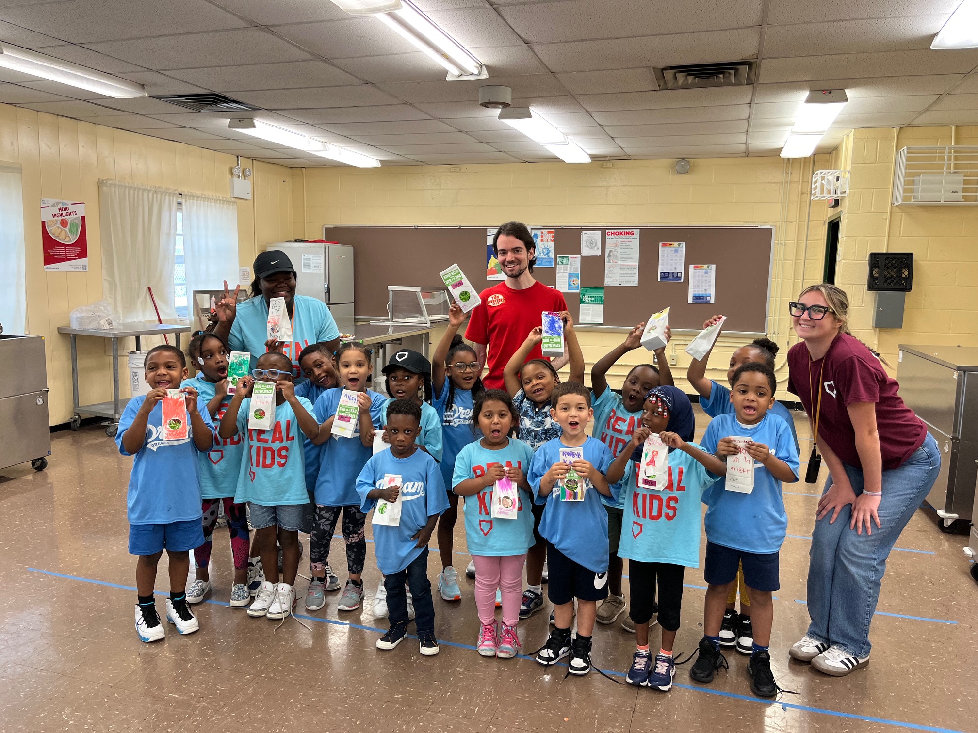 Children and adults holding handmade crafts indoors.