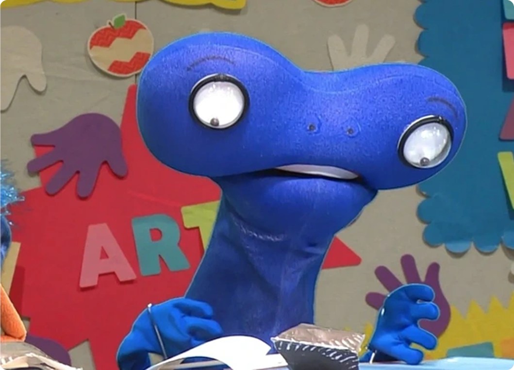 Blue puppet with large eyes, colorful background.